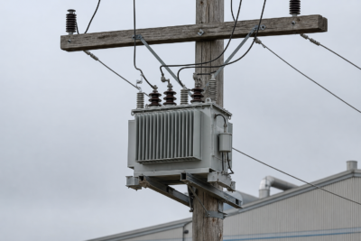 Pole mounted distribution transformer on utility pole with high voltage bushings